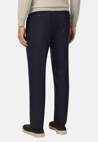 Jūras zilas bikses ar taisnu griezumu, gludu tekstūru un divām aizmugurējām kabatām. Saskaņotas ar tumšiem apaviem neformālam izskatam.