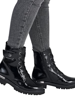 Des bottes de cheville en cuir verni noir présentent un design à lacets avec une fermeture éclair sur le côté, une semelle robuste et un accent métallique sur le talon.