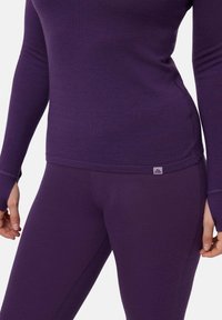 Violetti pitkähihainen paita ja legginssit, jotka on valmistettu pehmeästä kankaasta. Asusteessa on istuva muotoilu ja pieni merkkilappu vyötäröllä.