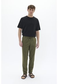 T-shirt nera a maniche corte, pantaloni con cordoncino verde oliva e sandali marroni. Vestibilità casual con un design semplice e tessuto leggero.