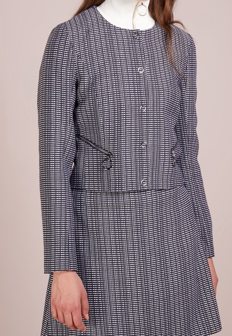Abito grigio e bianco con motivo, maniche lunghe, scollo rotondo, davanti con bottoni e dettaglio con zip laterale. Tessuto morbido, vestibilità sartoriale.