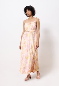 Robe maxi avec un motif floral en rose et jaune, réalisée en tissu léger. Comprend des bretelles ajustables et une taille élastique.