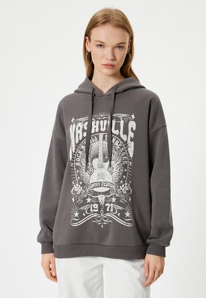 Sudadera gris con diseño impreso en blanco que incluye una guitarra y estrellas. Corte relajado, capucha con cordón y puños acanalados. Material suave de mezcla de algodón.