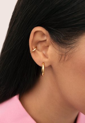 Pendientes de aro de oro con un acabado liso y brillante. Un pendiente es un pequeño cuff, mientras que el otro tiene un diseño de aro clásico y más grande.