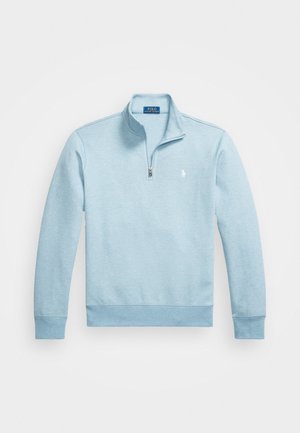 Ljusblå bomullspullover med kvartdragkedja, ribbade ärmslut och midja. Har en liten broderad logotyp på vänster bröst.