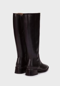 Bottes en cuir noir jusqu'au genou avec une finition lisse, un talon large et un discret détail de couture à l'arrière. Présente un design à bout rond.