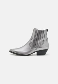 Botines metálicos plateados con puntera puntiaguda, detalles ondulados y paneles elásticos con rayas verticales. Tacón bajo tipo bloque. Textura suave.