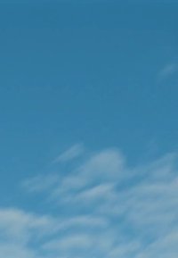 Ciel bleu clair avec des nuages blancs doux et légers éparpillés partout. L'ambiance générale est lumineuse et sereine.
