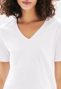 Witte v-hals t-shirt met korte mouwen, gemaakt van zachte stof, met een gladde textuur en een aansluitend ontwerp, dat een minimalistische uitstraling benadrukt.