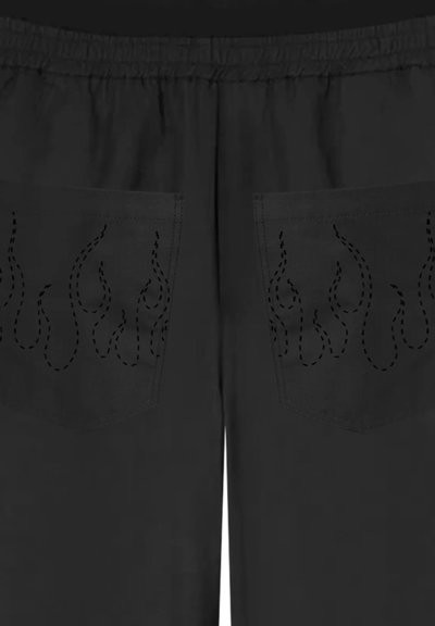 Pantaloni della tuta neri con design a forma di fiamma ricamati sulle tasche posteriori. Il materiale è liscio e presenta una vita elasticizzata.