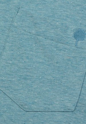 Helles blaues, strukturiertes Gewebe mit einer aufgenähten Tasche und einem dekorativen gestickten Baumdesign sowie dunkleren blauen Sprenkeln.