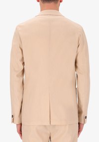 Giacca da abito beige con uno spacco singolo sul retro, maniche lunghe e polsini abbottonati. Realizzata in tessuto testurizzato, presenta una vestibilità su misura.