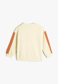Sudadera de color crema con tejido texturizado, que presenta rayas de color naranja quemado en las mangas y un escote redondo.