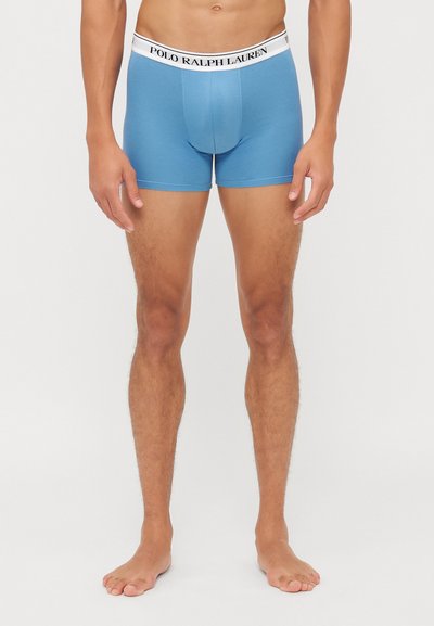 Boxeri scurți de culoare bleu deschis cu un elastic alb pe care este inscripționat textul negru "POLO RALPH LAUREN". Construiți dintr-un material moale și elastic.