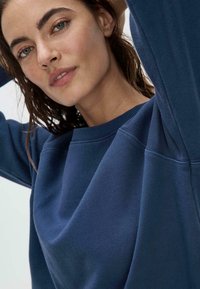 Felpa blu navy con scollo a girocollo a costine e maniche raglan, realizzata in un tessuto morbido. Caratterizzata da una vestibilità comoda e una texture liscia.