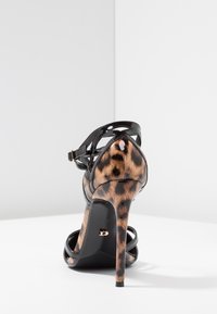 Sandali con tacco alto, caratterizzati da una tomaia in pelle verniciata nera e un tacco con stampa leopardata. Design con strappi e chiusura con fibbia alla caviglia.