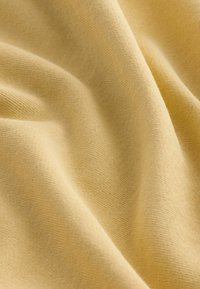 Tejido de punto de un suave y claro color beige con suaves pliegues y una textura fina y uniforme.