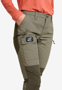 Gröna utomhus byxor med texturerad finish, som har flera fickor, en ficka med dragkedja på sidan, och en logopatch på låret.
