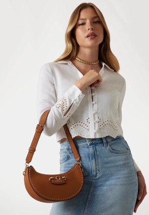 Sac à main en simili cuir marron avec une forme incurvée, matériel en acier inoxydable et détails cousus. Le sac est équipé d'une bandoulière et d'un accent logo.