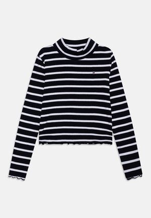 Zwart-wit horizontaal gestreepte cropped top met lange mouwen, hoge kraag en klein geborduurd logo op de borst.