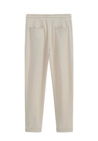 Pantalons de survêtement beige clair avec une taille élastique, deux poches avant et un tissu doux et texturé. Design de jambes fuselées avec des ourlets côtelés.