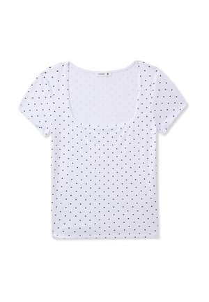 T-shirt bianca a maniche corte con scollo rotondo, caratterizzata da un motivo di pois neri su tutta la superficie. Tessuto morbido e elasticizzato.