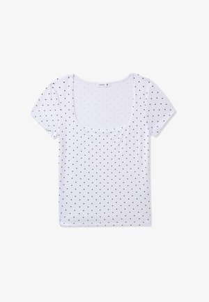 T-shirt bianca a maniche corte con scollo rotondo, caratterizzata da un motivo di pois neri su tutta la superficie. Tessuto morbido e elasticizzato.