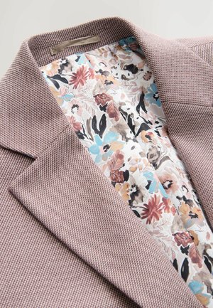 Blazer texturé rose clair avec col cranté ; doublure à motif floral dans des couleurs douces, avec des accents bleus, roses et bruns.