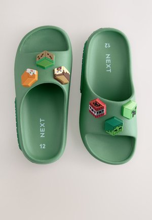 Rohelised plastist sandaalid tekstureeritud jalataldadega, millel on neli värvilist eemaldatavat plokki peal, sealhulgas videomängu pikslitud kujundused.