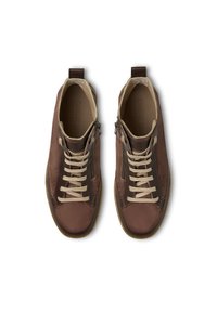 Scarpe alte marroni realizzate in una combinazione di materiali lisci e testurizzati. Presentano lacci beige, cerniere laterali e una suola in gomma.