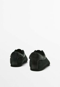 Pari mustia matalakorkoisia kenkiä, joissa on verkkopaneelit sivuilla ja sileät kantapaneelit, esillä takaa valkoista taustaa vasten.