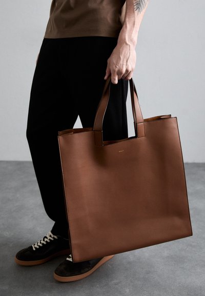 Borsa tote in pelle marrone con design minimalista, forma rettangolare e manici corti. Presenta un logo discreto sul davanti.