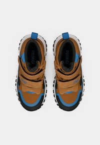 Sneakers per bambini marroni e blu con suole nere e chiusure in velcro visti dall'alto su uno sfondo bianco.
