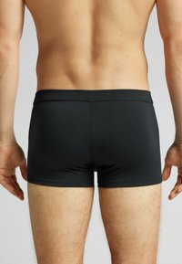 Svarta boxershorts i slät tyg, med en enkel design, mjuk midja och utan synliga mönster eller detaljer.
