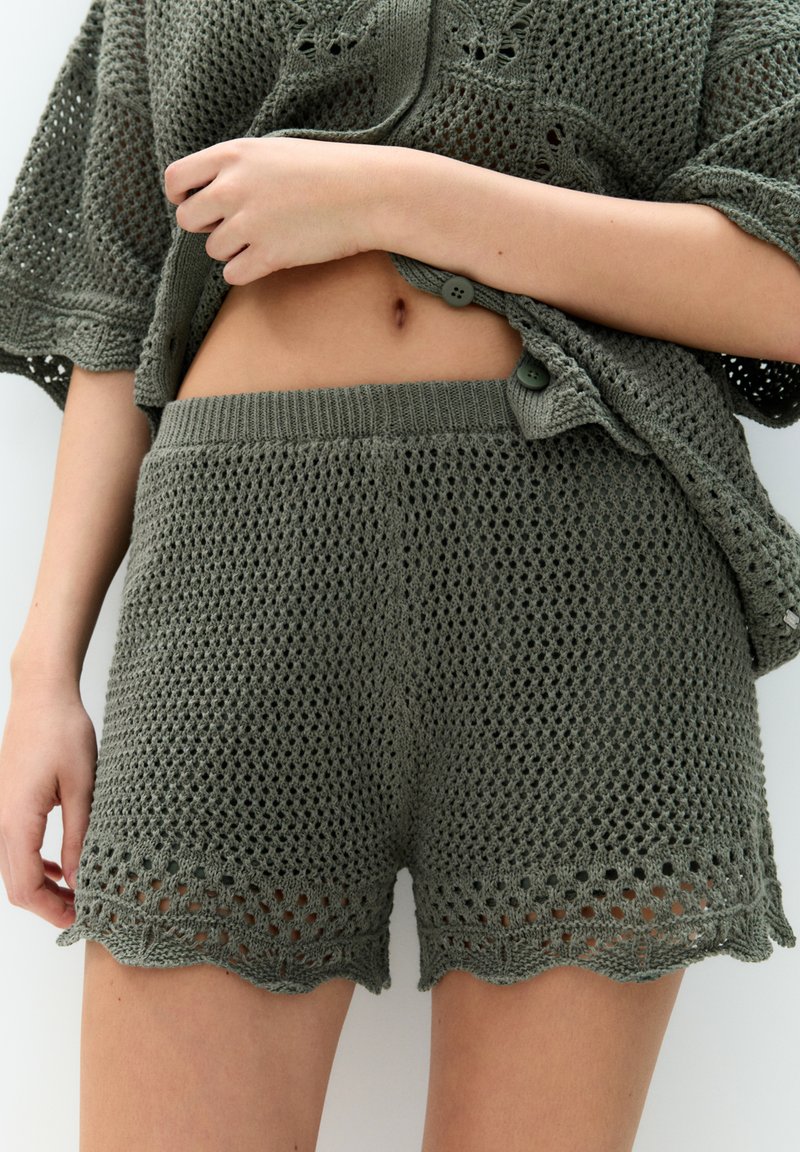 Khaki virkad shorts med en texturerad mönster, vågig nederkant och elastisk midja. Styld med en matchande öppenstickad topp.