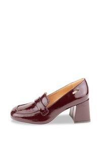 Mocasines de charol burdeos con tacón cuadrado, diseño de puntera cosida y un pequeño acento lateral, con una textura suave y brillante.