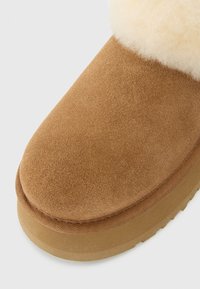 Ingrandimento di un boot in suede beige con suola spessa e rivestimento morbido di colore crema attorno all'apertura.