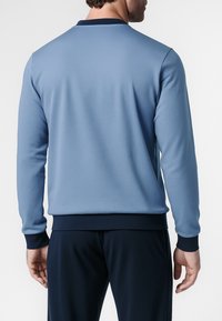 Felpa blu con una texture morbida, collo rotondo e polsini e orlo blu scuro. Presenta una finitura liscia e una vestibilità comoda.