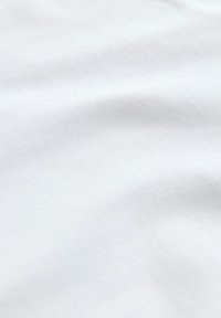 Fehér szövet textúrált mintával, diszkrét gyűrődésekkel és sima felülettel. Az anyag könnyűnek és lélegzőnek tűnik.