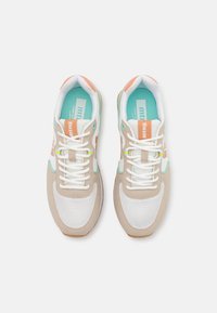 Baskets avec une tige en mesh et en daim beige, accents blancs, doublure turquoise, détail de logo orange et semelle en caoutchouc texturée.