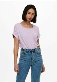 T-shirt corto a maniche corte di colore viola chiaro con scollatura rotonda e risvolti, abbinato a jeans in denim blu a vita alta. Tessuto di superficie liscia.