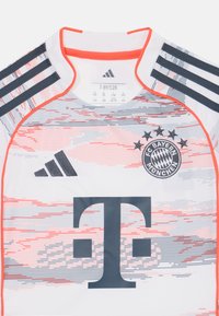 Maillot Adidas du FC Bayern Munich présentant une base blanche, des accents corail, des lignes graphiques, trois bandes noires sur les épaules et le badge du club.