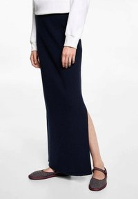 Tmavě modrá, žebrovaná maxi sukně s bočním rozparkem, kombinovaná s vzorovanými botami na slip, které mají vínový lem.