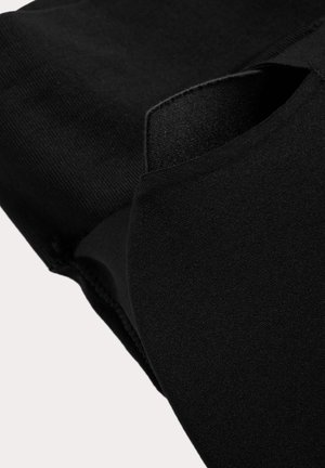 Close-up van zwarte stof met gelaagde, gevouwen textielsecties met gladde en geribbelde texturen.