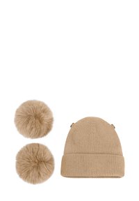 Cappello invernale beige lavorato a maglia con due pompon in pelliccia sintetica beige rimovibili su sfondo bianco.