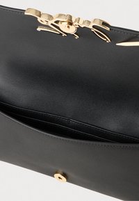 Fekete bőr kézitáska aranyszínű hardverrel, fodros tetejű zárással és egyetlen rekesszel. Sima textúrájú és lekerekített formájú.