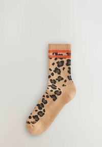 Beige leopard print socks with black spots, featuring an orange striped cuff. Made from a textured knitted material.