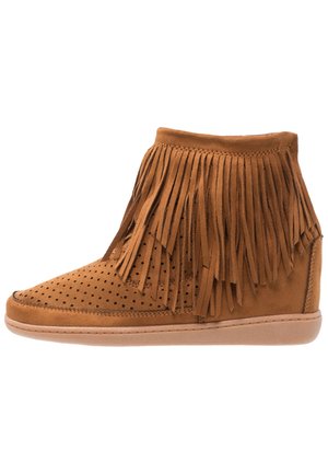 Brązowy zamszowy botek na koturnie za kostkę z frędzlami i perforowanym przodem, płaska gumowa podeszwa, widok z boku.
