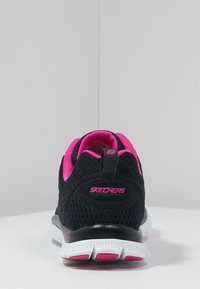 Czarny sneaker Skechers z różowymi akcentami, z materiału siatkowego, teksturowana powierzchnia i biała gumowa podeszwa. Posiada pętelkę oraz logo na pięcie.