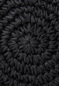 Czarny tkany dywan z teksturowanym, okrągłym wzorem z ciasno zawiązanymi elementami i gładką, płaską powierzchnią.
